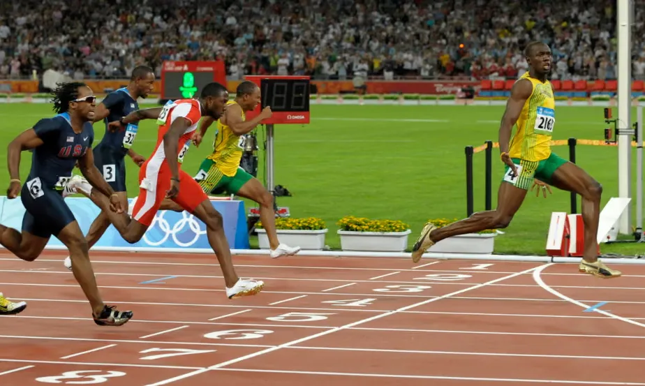 Usain Bolt, right, crosses the finish line to win gold in the men’s 100m final in Beijing.